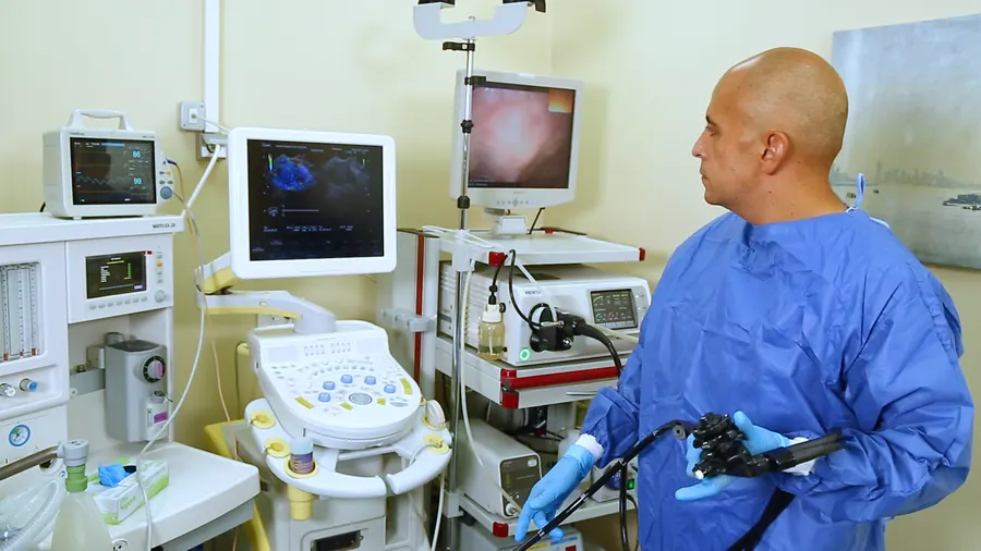 An endoscopist holds an endoscope beside the endoscopy tower