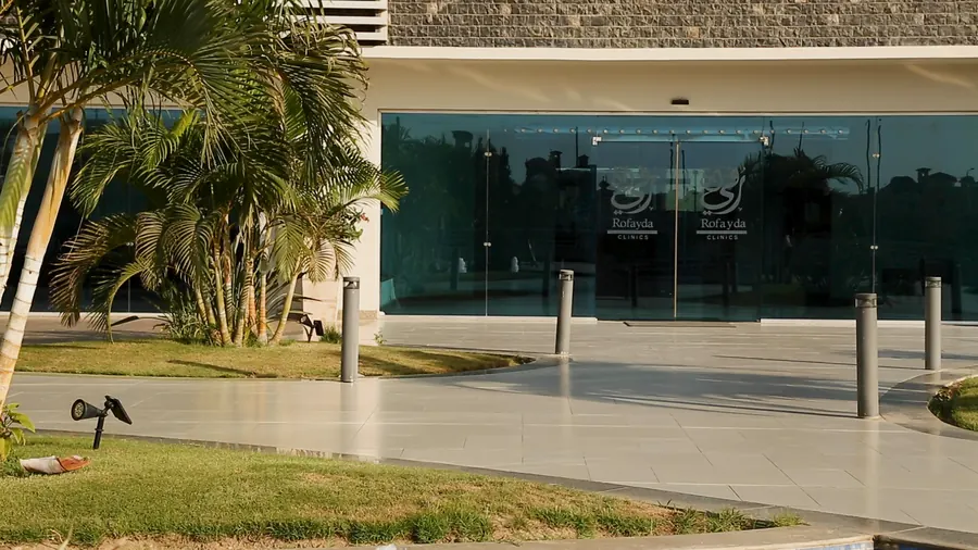 The glass entrance of the clinics building, with palm trees